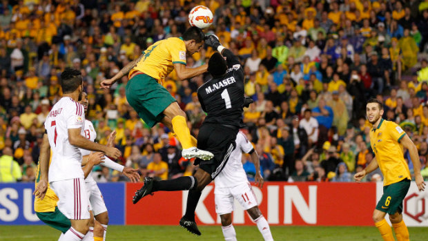 Tim Cahill flies high for a header against UAE goalkeeper Majed Naser.