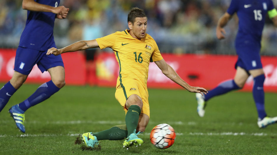 Caltex Socceroos forward Nathan Burns slips over on the ANZ Stadium surface as he's taking a shot on goal.