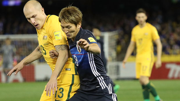 Socceroos midfielder Aaron Mooy fights for the ball with Japan's Genki Haraguchi.