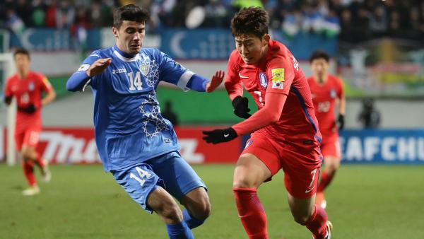 Son Heung Min of South Korea and Javokhir Sokhibov of Uzbekistan compete for the ball.