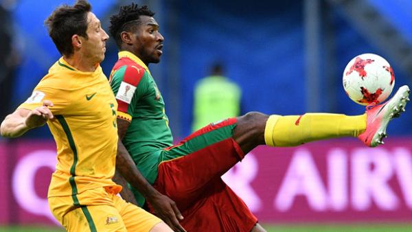Mark Milligan fights for the ball with Cameroon's Andre Zambo.